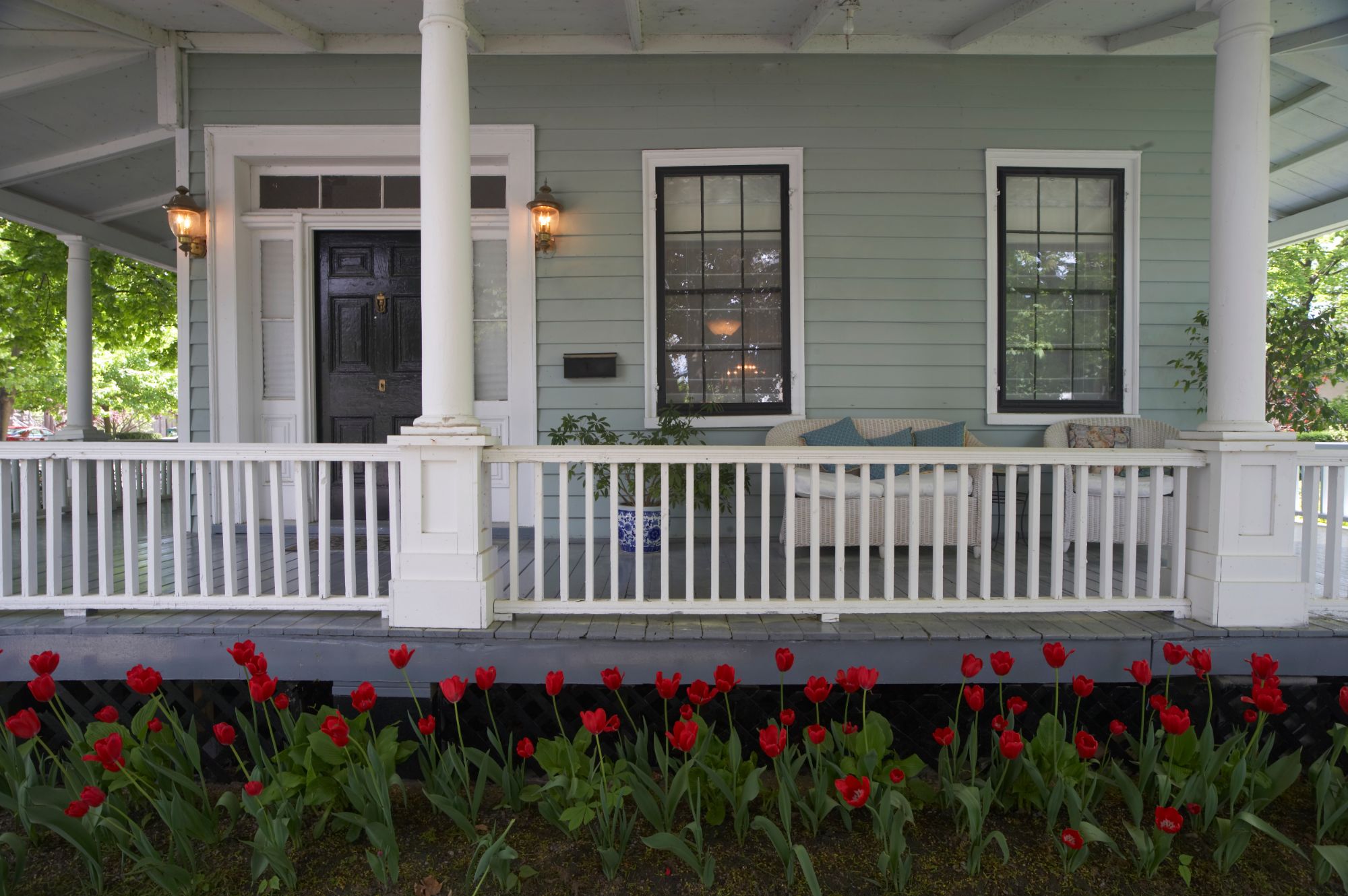 White wraparound porch with red tulips in bloom