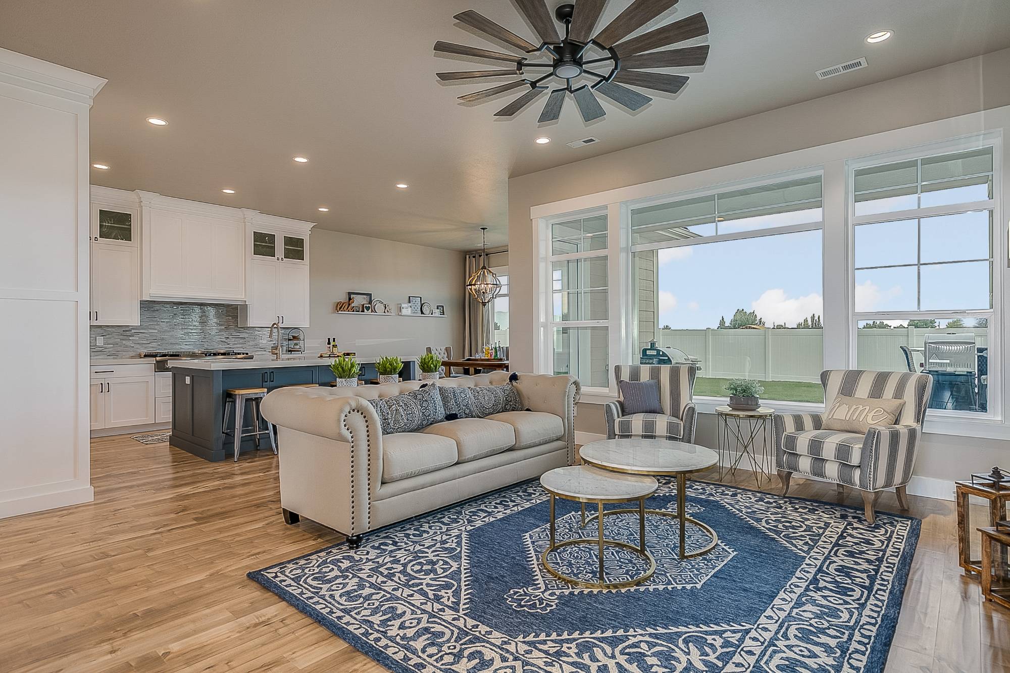 Open concept living room with blue area rug and windmill ceiling fan