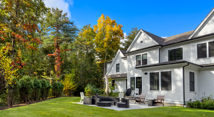 Large white Montgomery County home with a landscaped backyard and patio in early fall
