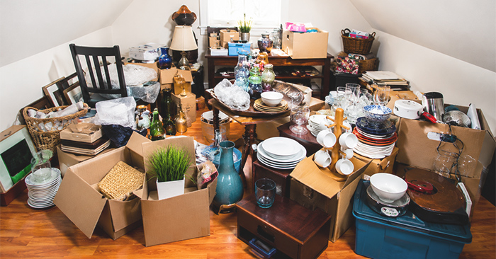 Cluttered room filled with boxes, dishes and belongings from a parent's house waiting to be cleaned out