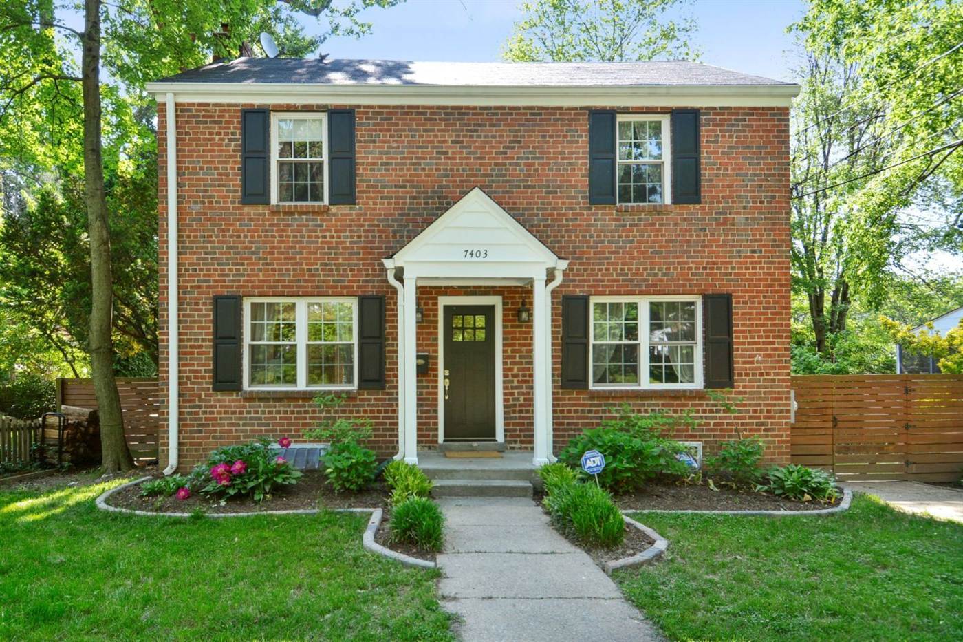Brick colonial home with black shutters and a garden entry