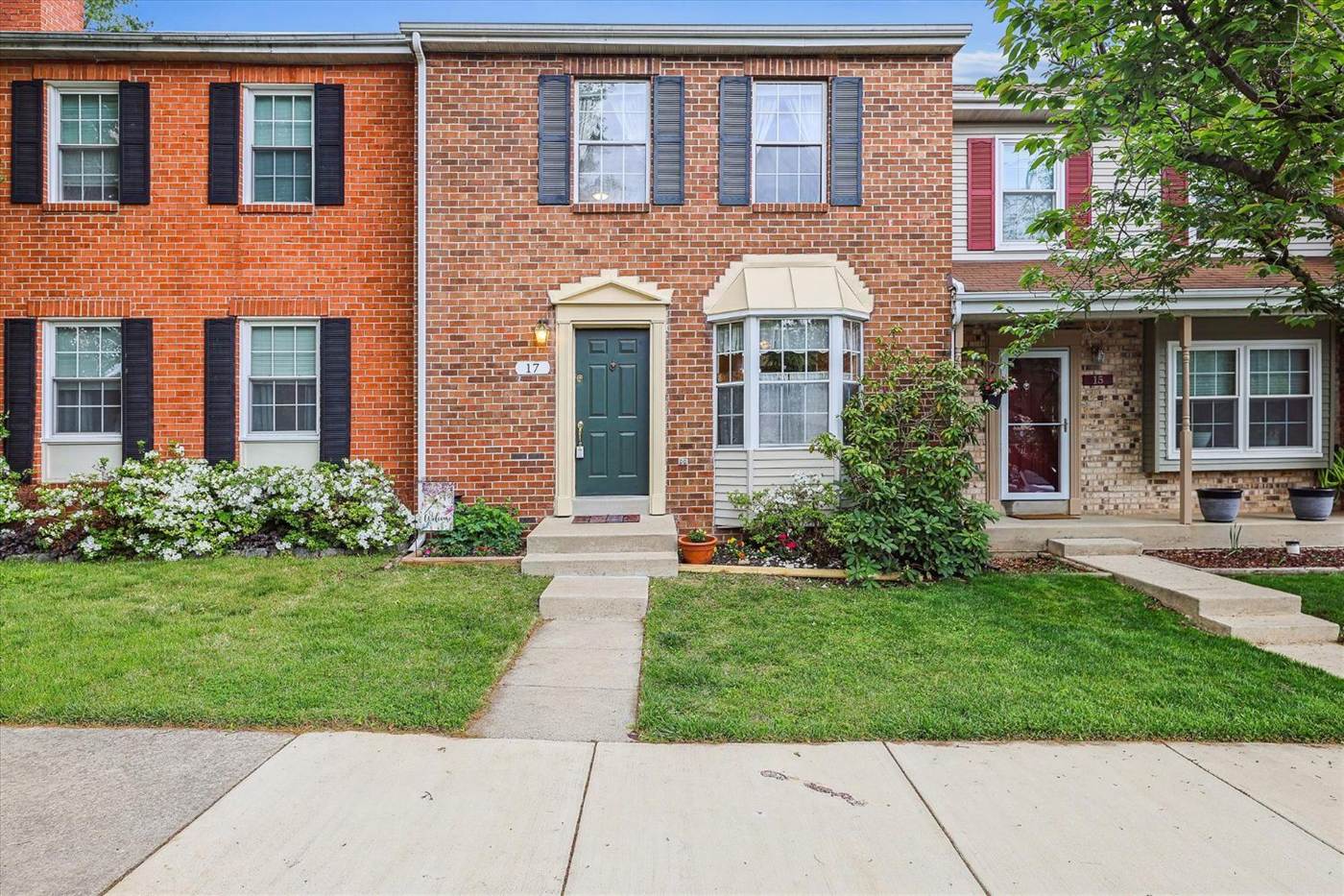 Brick townhouse with a green door and blooming azaleas
