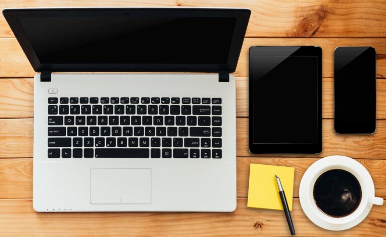 Laptop, tablet, smartphone and coffee on a wooden desk, used for comparing mortgage rates online