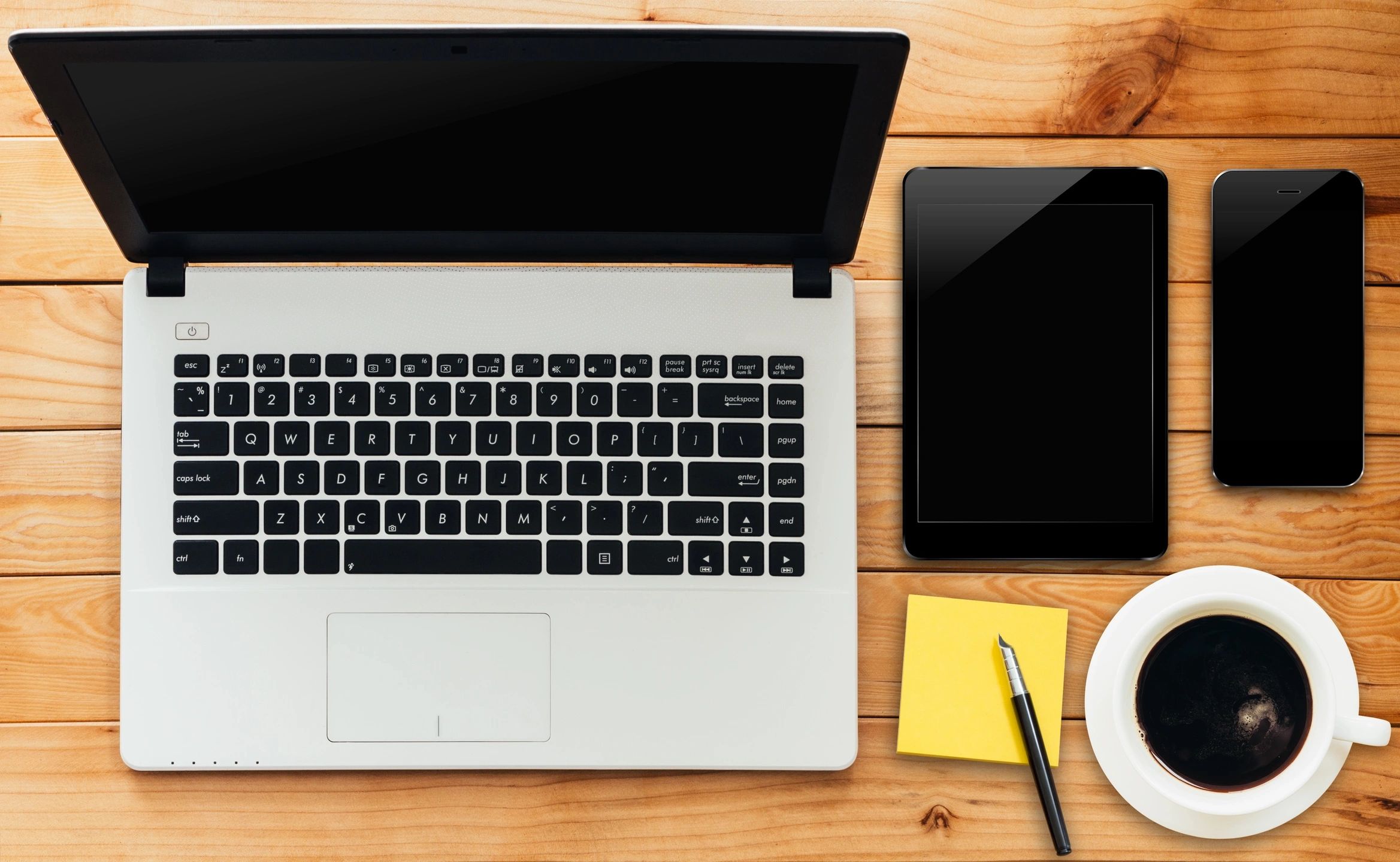 Laptop, tablet, smartphone and coffee on a wooden desk, used for comparing mortgage rates online