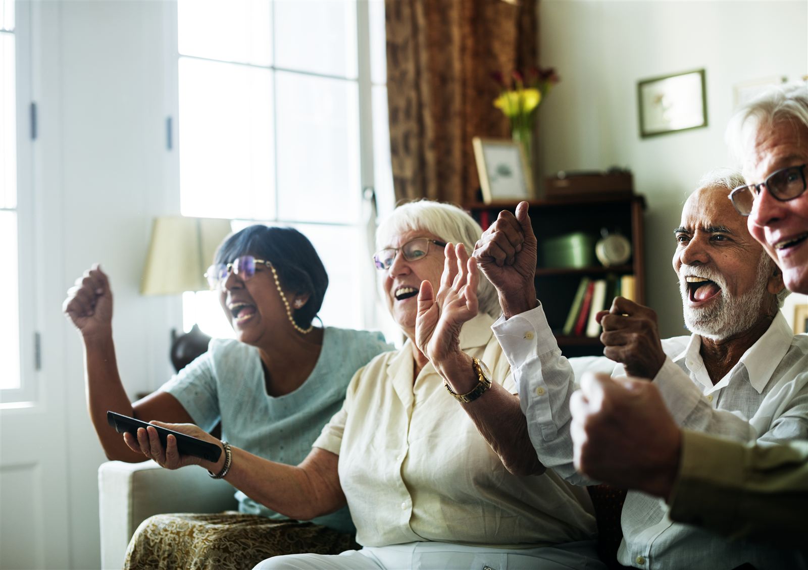 Active seniors cheering while watching TV together